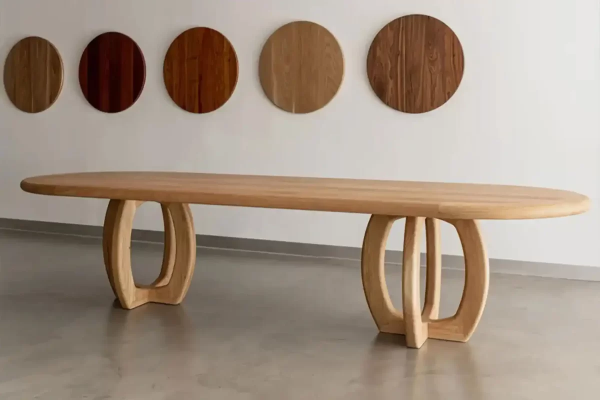 Bespoke solid timber dining table displayed with a wall of timber finish samples